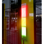 Vertically mounted SL2 indicator light on yellow metal post showing red, yellow, and green illuminated segments with a metal grid fence in the background.