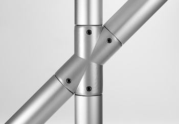 Close-up of a silver metallic cross-connector joining four tubes at 45° and 135° angles with black screws securing the components