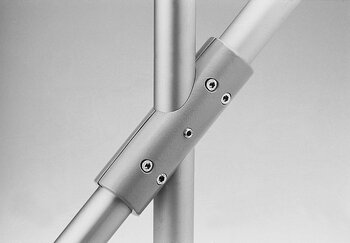 Close-up of a metallic tube connector joining three cylindrical tubes at 45° and 135° angles with hex screws, smooth matte finish